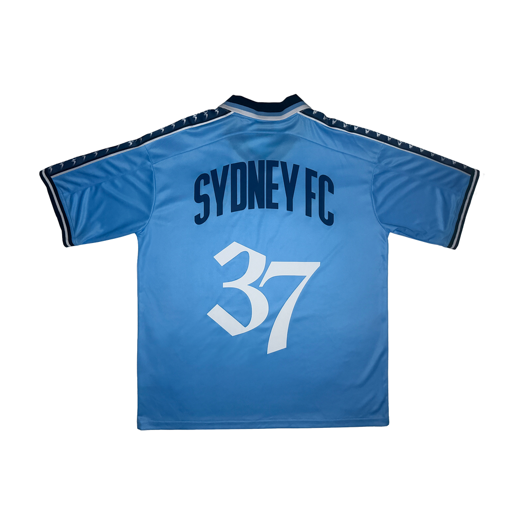 The back of a light blue Sydney FC soccer jersey featuring the team name in navy blue and the number 37 in white, displayed on a clean white background.